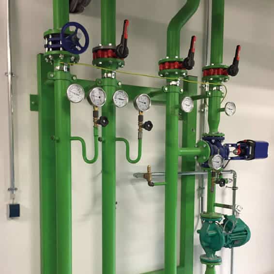 Vorgefertigte Pumpengruppen mit grünen Rohren, Ventilen und Manometern