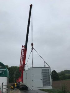 Roter Kran hebt einen grauen BHKW-Container