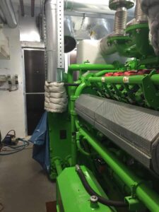 Grüner Jenbacher-Motor mit isolierter Leitung im Maschinenraum