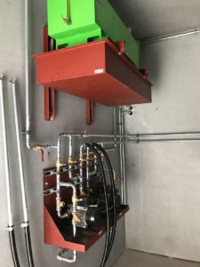 An der Wand montierte Pumpengruppe mit roter Auffangwanne