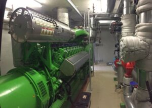Grüner Jenbacher-Motor mit Generator im Maschinenraum