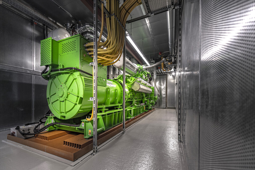 Grünes Jenbacher BHKW-Modul mit Generator in einem Maschinenraum