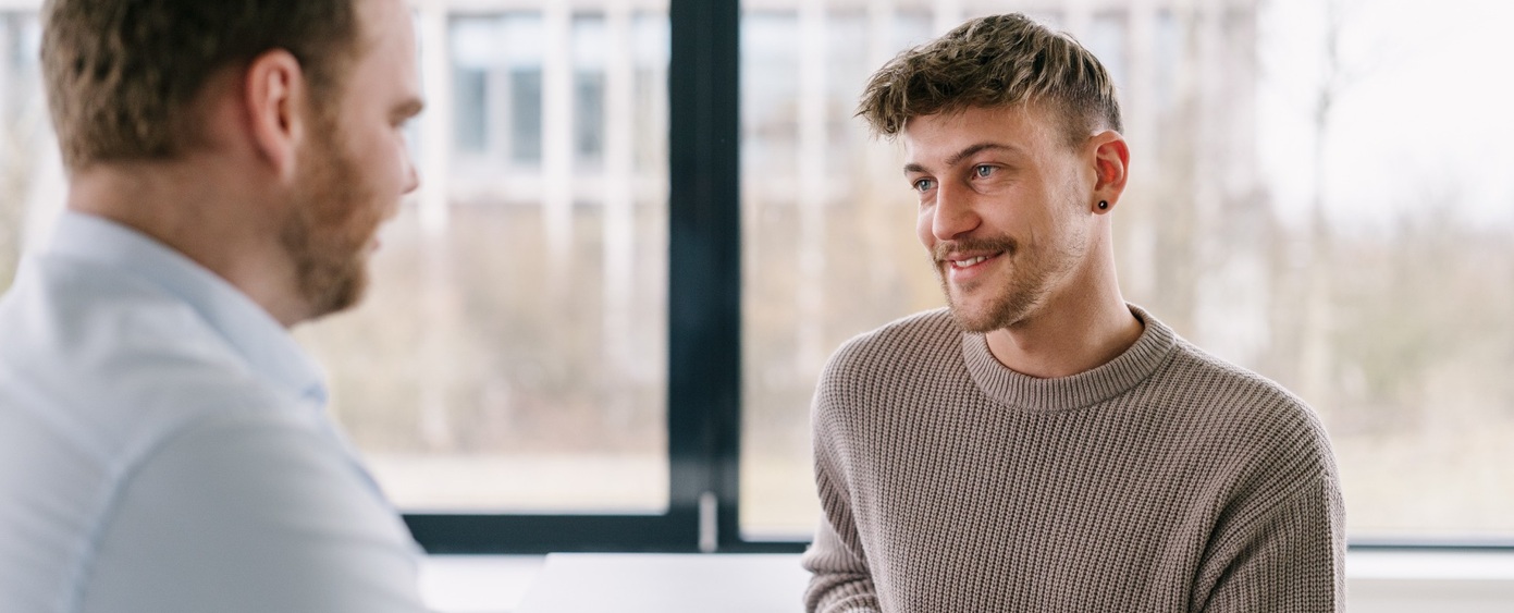 Zwei Männer im Gespräch an einem Fenster