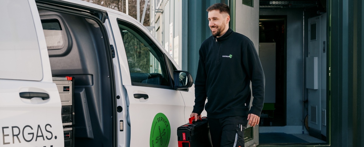 Lächelnder Mann mit Werkzeugkoffer neben einem Transporter mit Energas-Schriftzug
