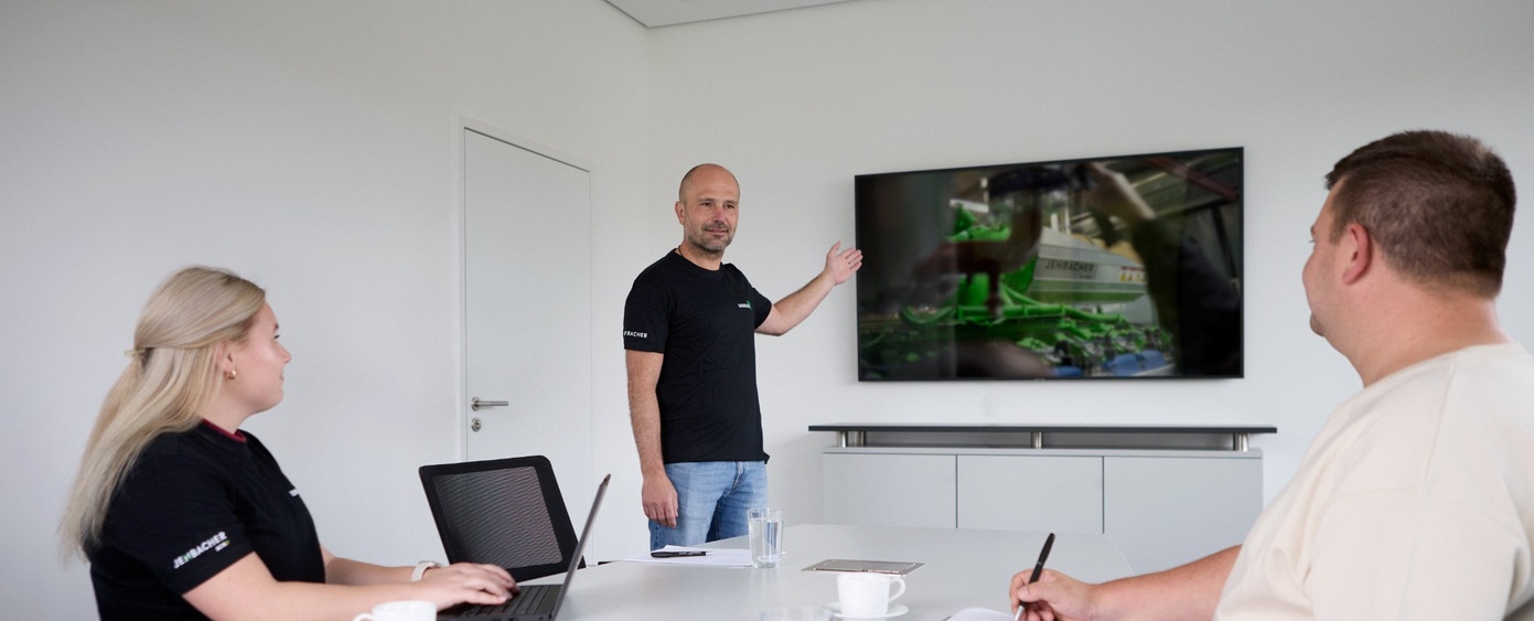 Mann präsentiert am Bildschirm vor zwei Personen im Besprechungsraum