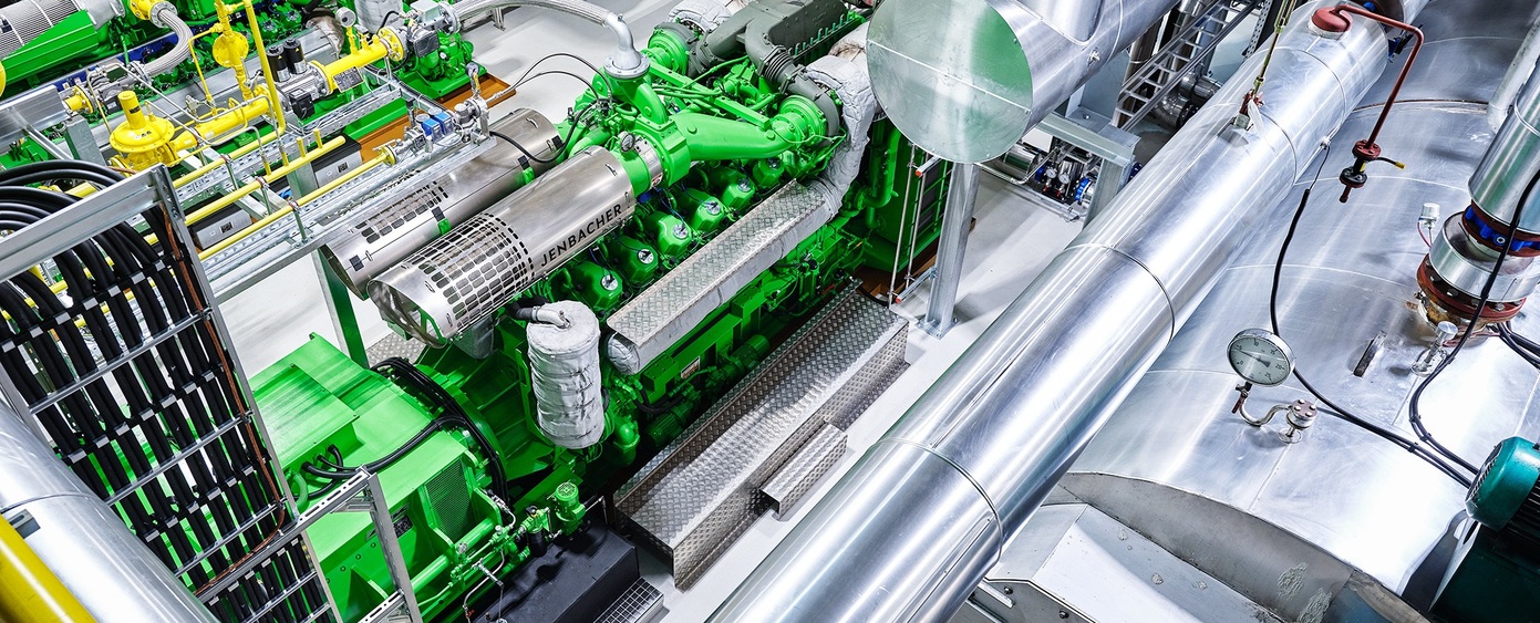 Blick von oben auf einen grünen Jenbacher Motor mit Rohrleitungen