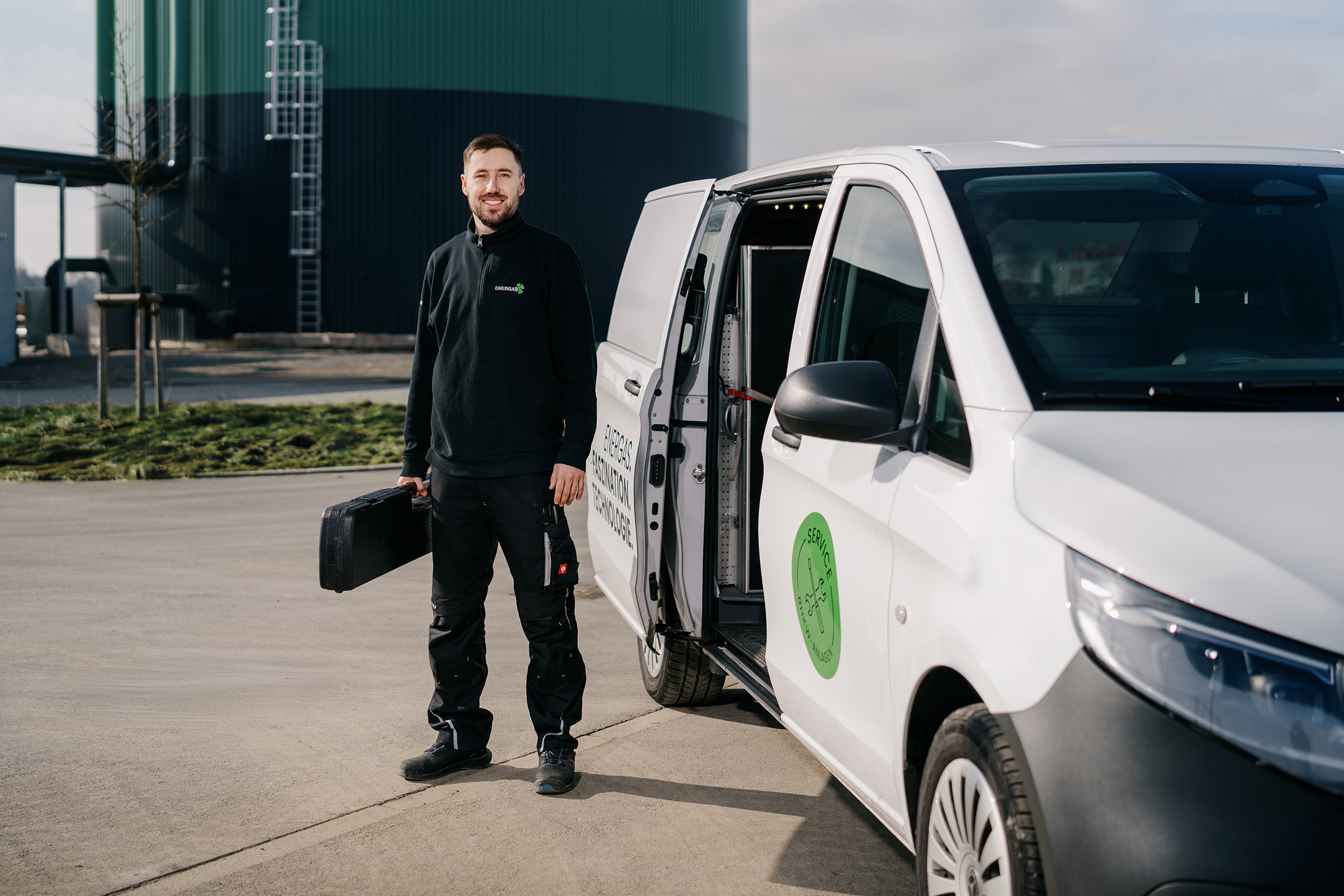 Mann mit Werkzeugkoffer neben einem weißen Transporter mit Energas-Logo