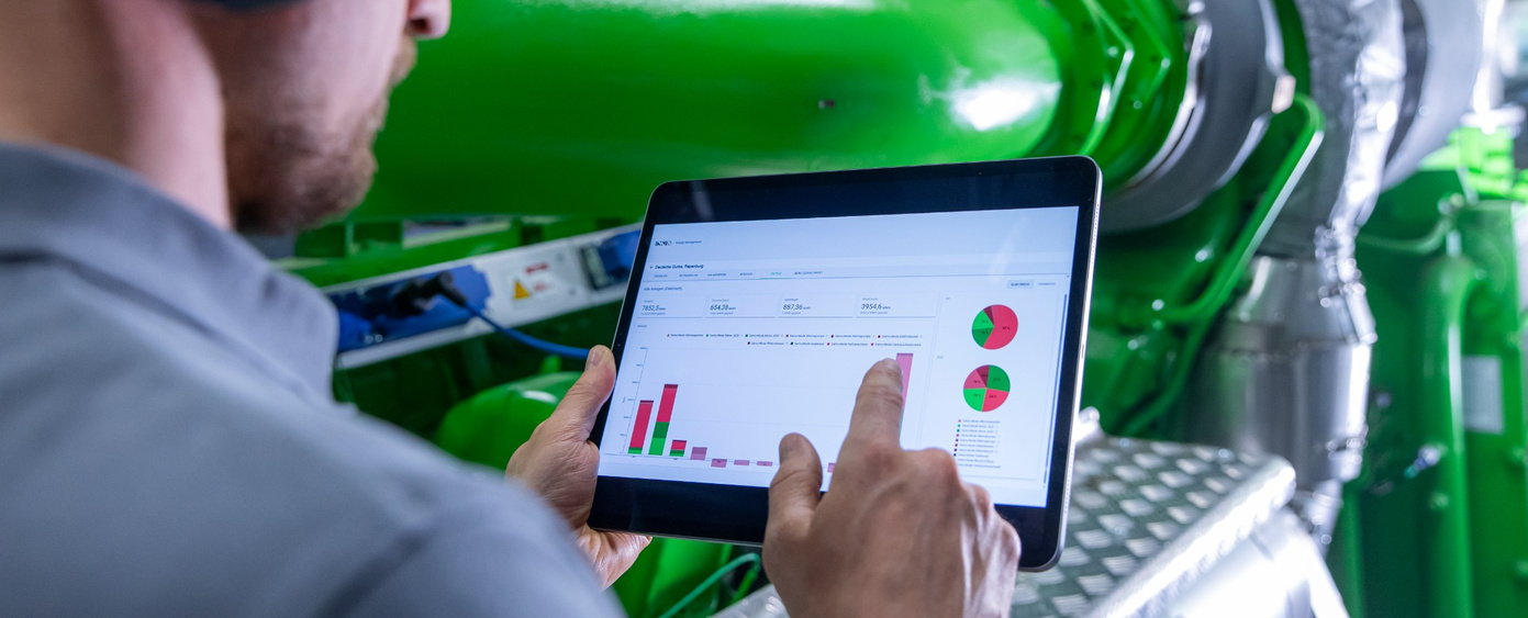 Tablet mit Balken- und Kreisdiagrammen vor einem grünen Motor