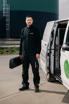 Mann in Arbeitskleidung mit Werkzeugkoffer neben einem Transporter mit Energas-Logo