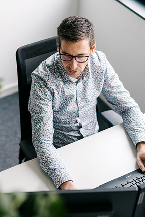 Mann mit Brille arbeitet konzentriert am Laptop