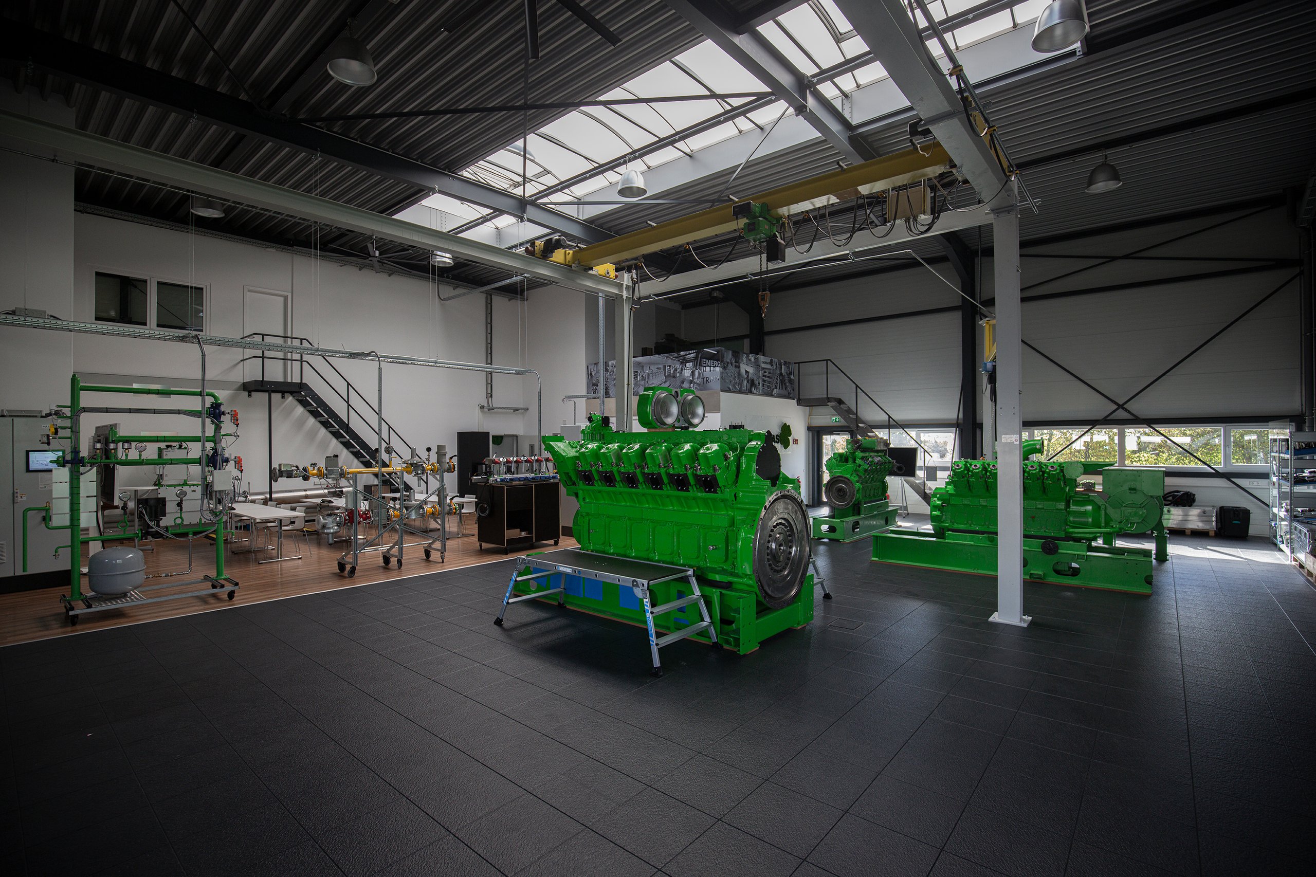 Schulungshalle des Trainingscenters mit grünen Jenbacher Motoren, gelbem Laufkran und Oberlichtern