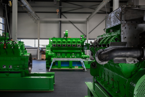 Mehrere grüne Motoren auf Gestellen in der Schulungshalle, rechts vorne ein Motor mit Abgasleitung